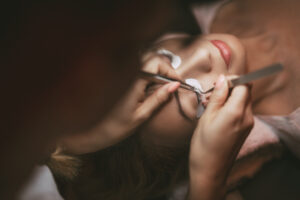 Beautician applying extended eyelashes to model. Close up.